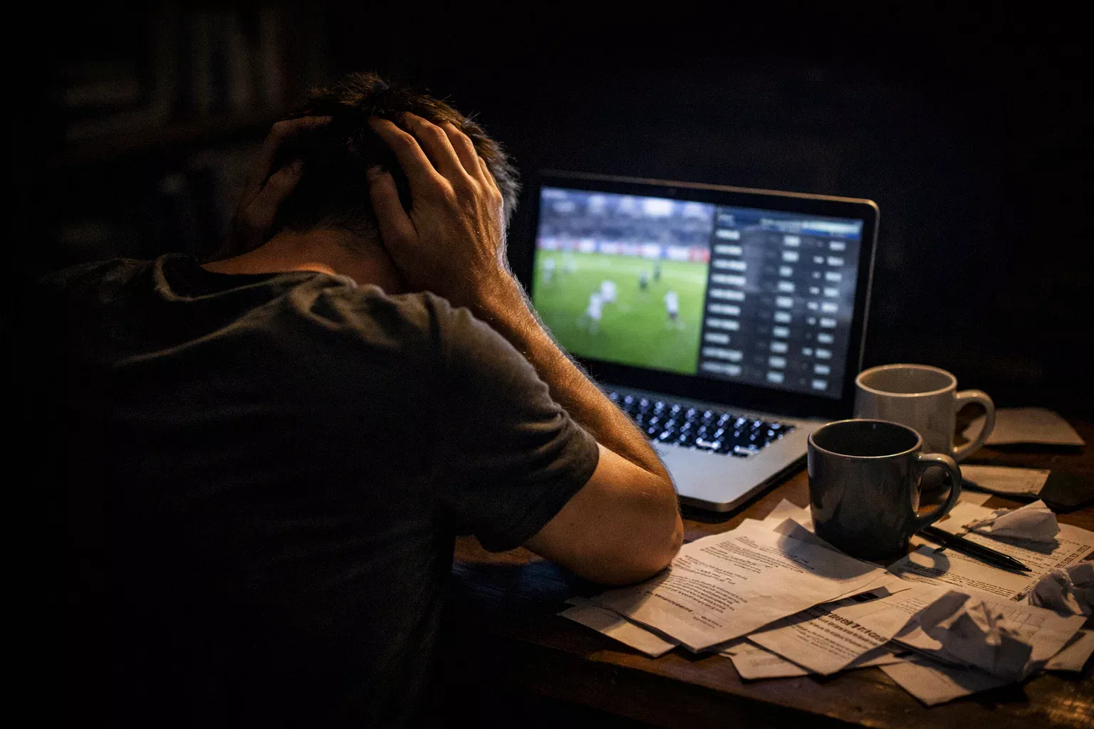 Gefrustreerde man met hoofd in handen bij laptop met wedstrijden